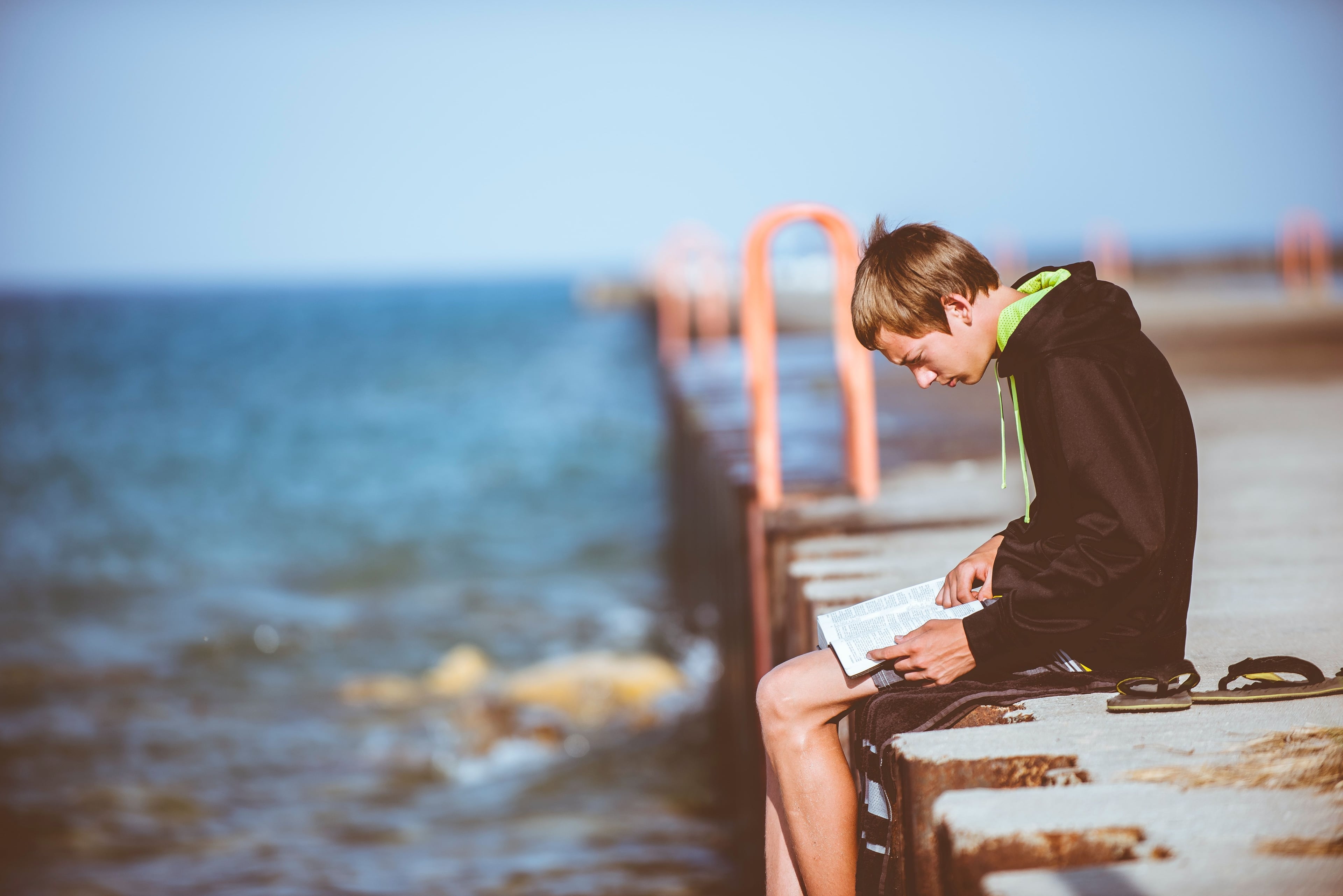 man sitting on a pier reading a book