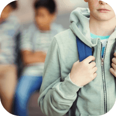 Portrait of sad schoolboy with schoolbag standing in campus