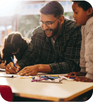 Group of elementary school kids stand around a table in a classroom, attentively following a lesson being taught by their teacher. Young students engaging in a fun activity of colouring and drawing.