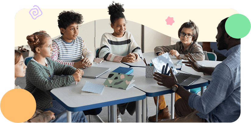 Diverse group of children sitting at table with male teacher in modern school classroom