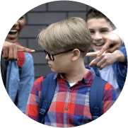 Schoolchildren pointing fingers at junior student, mocking smart boy, bullying