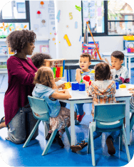 Diverse classroom with children and a teacher. Kids of various ethnicities learning together. Teacher guiding students in a colorful classroom setting. Teacher working with elementary school children.
