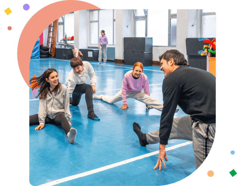 Students stretching with teacher in school gym class.