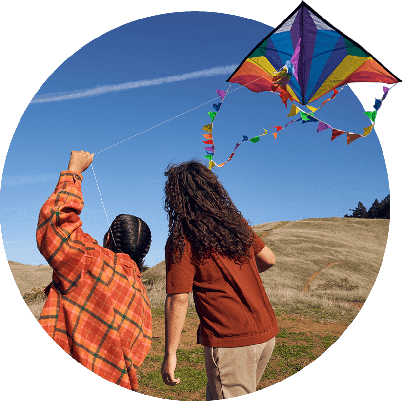 Young Teenager Siblings Flying Kite Together in the Valley