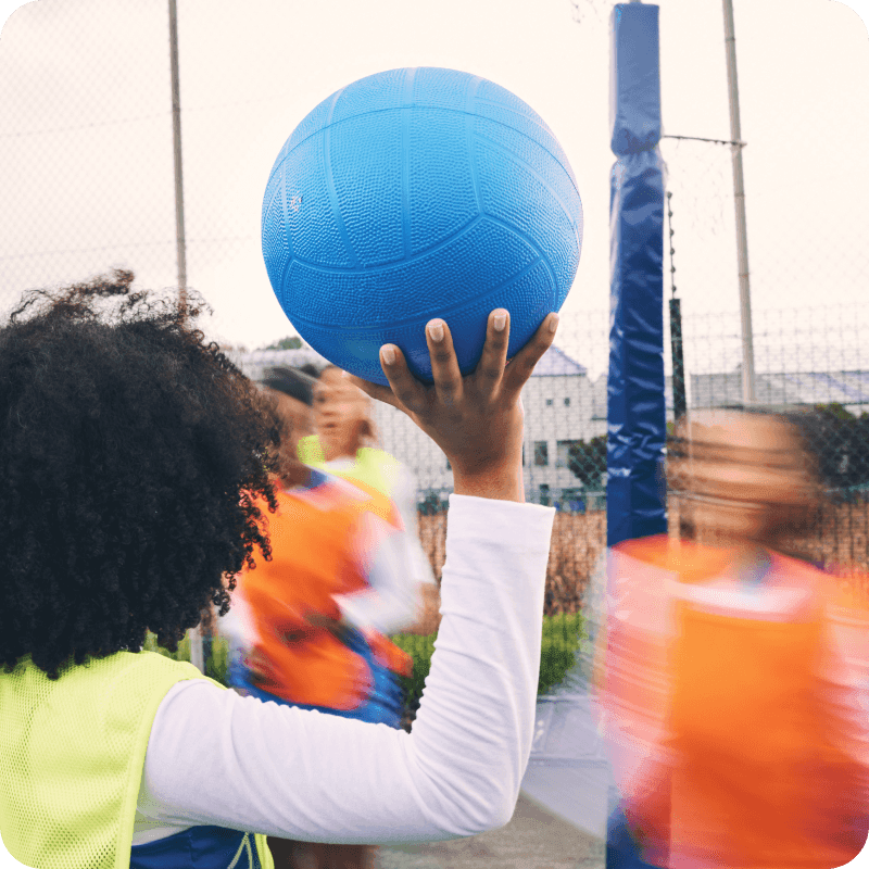 Sports, fitness and netball match by women at outdoor court for training, workout and practice. Exercise, students and girl team with ball for competition, speed and performance while active at field