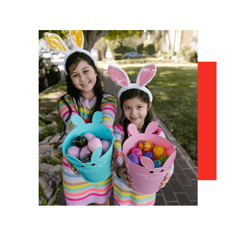 two adorable girls with bunny headbands showing easter eggs